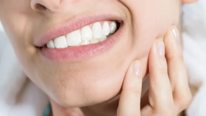 Woman experiencing jaw pain and tension caused by TMJ disorder